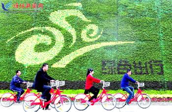 市民騎公共自行車路過市人民廣場一處花壇。記者 張馳